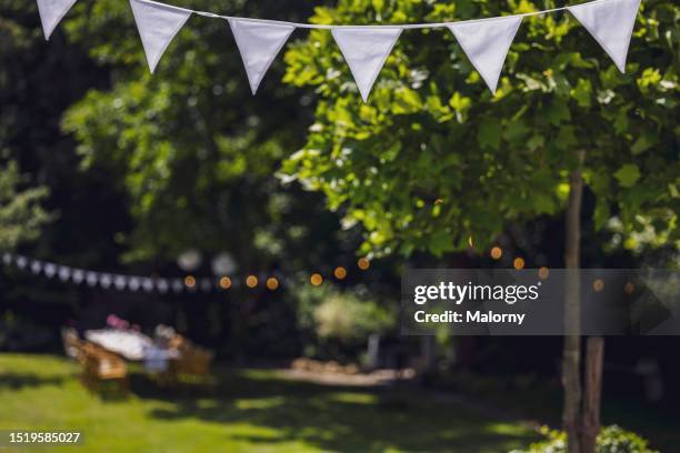 decorated garden with set table, flag garland and paper lanterns. garden party, summer festival, birthday party, baptism or wedding. - backgrounds stock-fotos und bilder