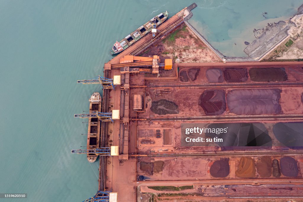 Vista aérea de materias primas metálicas apiladas en la terminal de carga