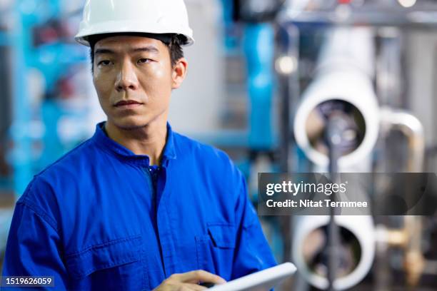 improve overall operational efficiency and minimize disruptions with preventive and predictive maintenance. portrait of a japanese service engineer working in a control room to perform daily operations for maintaining the quality of the boiler. - overall stockfoto's en -beelden