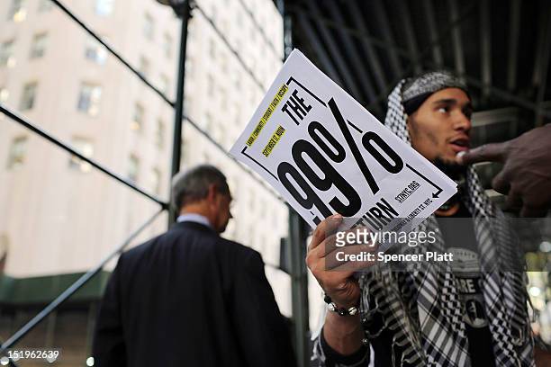 Member of the group "Occupy Wall Street" hands out flyers announcing the "99% Return" on a sidewalk near Wall Street on September 13, 2012 in New...