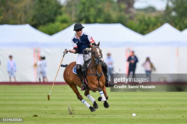 Prince William, Prince of Wales reaches for the ball as he takes part in the Out-Sourcing Inc. Royal Charity Polo Cup 2023 at Guards Polo Club on...