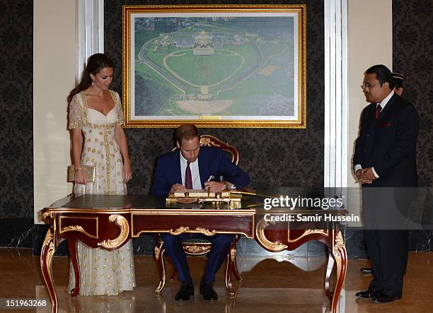 Prince William, Duke of Cambridge and Catherine, Duchess of Cambridge sign the visitors' book during an official dinner hosted by Malaysia's Head of...