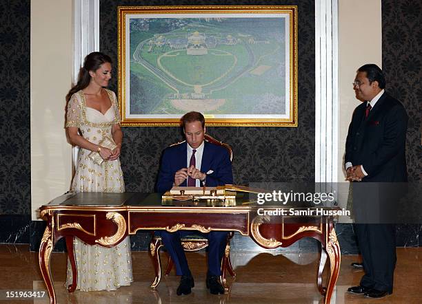 Prince William, Duke of Cambridge and Catherine, Duchess of Cambridge sign the visitors' book during an official dinner hosted by Malaysia's Head of...