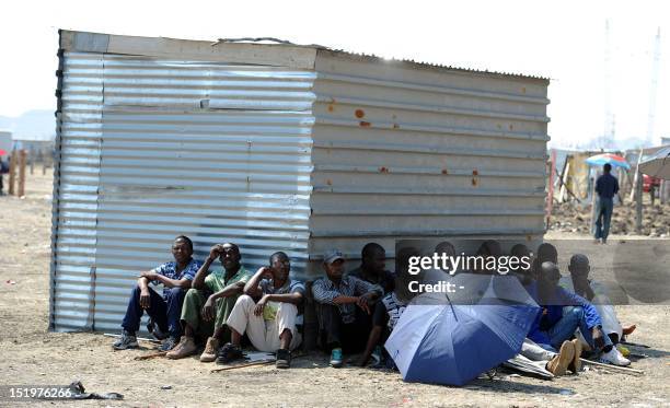 Striking Lonmin platinum mine workers sit on September 14, 2012 in the shade in Marikana, listening to their union representatives reporting back...