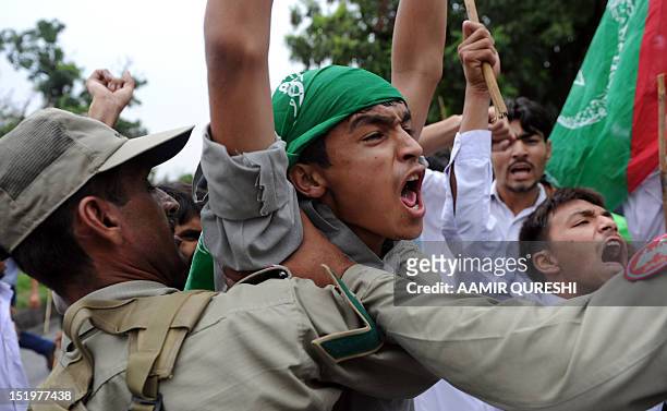 Pakistani soldiers hold back Muslim protesters shouting anti-US slogans as they attempt to reach the US embassy during a demonstration against the...