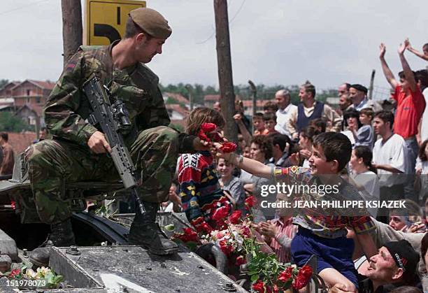 An ethnic Albanian boy gives red roses to a British soldier as first NATO troops are deployed in Kosovo's capital of Pristina 13 June 1999. The...