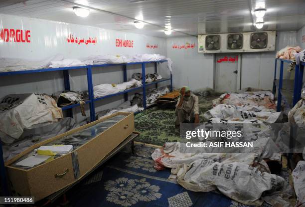 Pakistani morner sits among the burnt bodies of those who perished in a garment factory fire at the EDHI Morgue in Karachi on September 14, 2012....