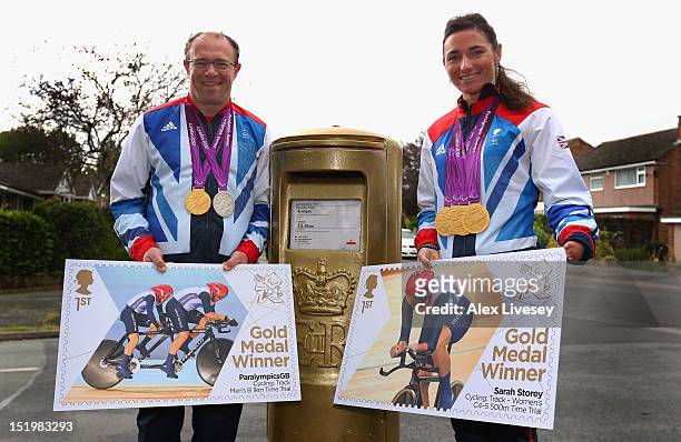 Sarah and Barney Storey pose with their Paralympic medals and stamp artwork next to a Royal Mail post box painted in honour of their Paralympic gold...