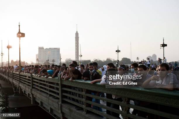 Hundreds of Egyptians watch the progress of clashes between protesters and riot police from the famous Kasr al Nil bridge, near the United States...