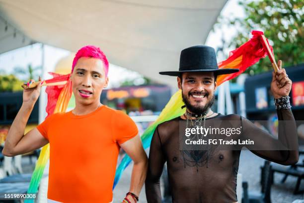 porträt von freunden im mittleren erwachsenenalter mit gay-pride-flagge im freien - annual latin pride festival stock-fotos und bilder