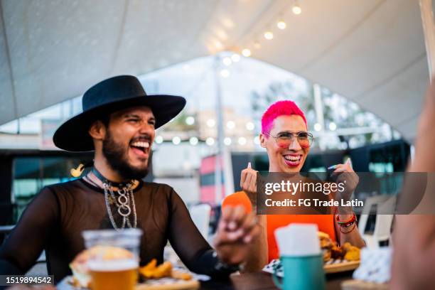 mid adult friends talking and eating at a festival - androgynous stock pictures, royalty-free photos & images