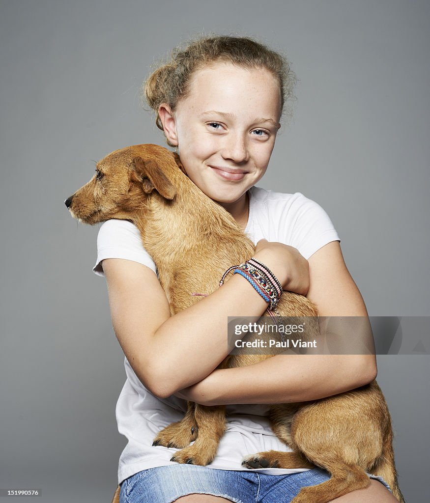 Young girl [10-12] cuddling pet dog