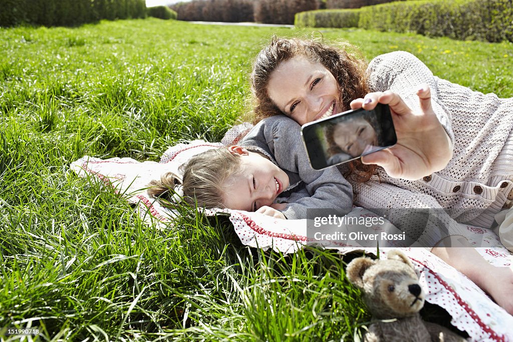 Daughter and mother with smartphone lying in grass