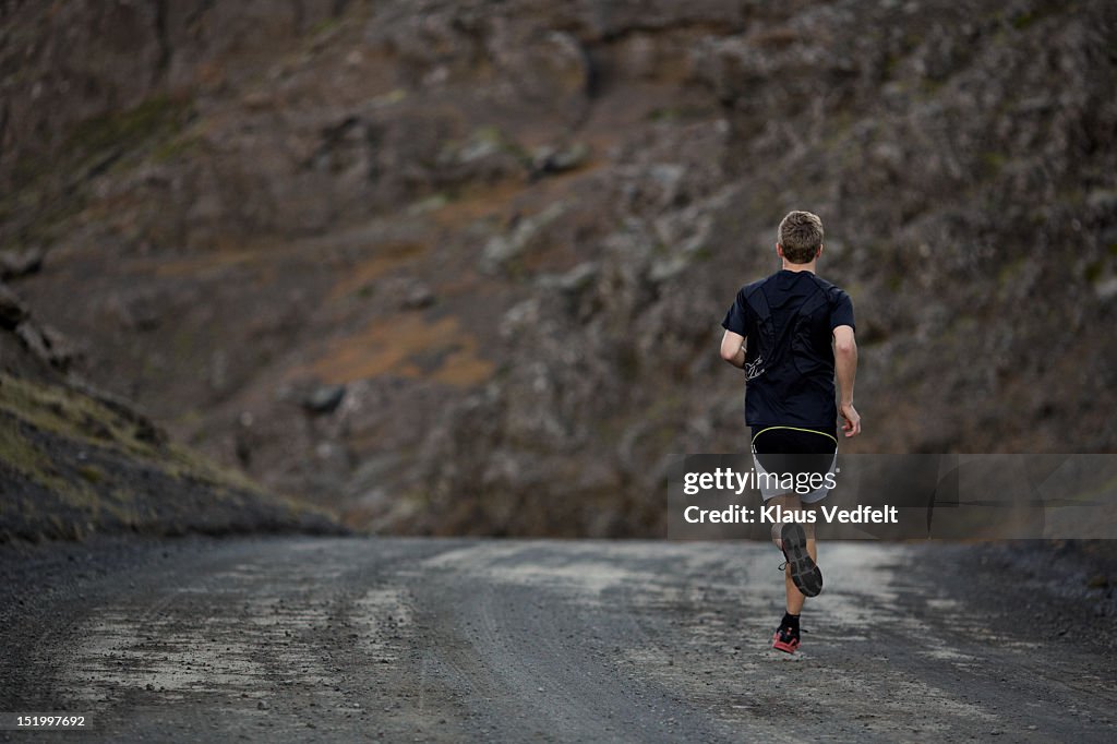 Male runner on mountain road, back view