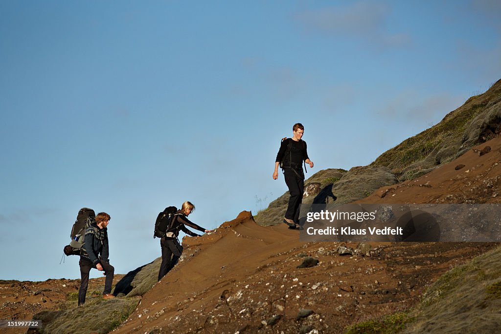 3 hikers walking on mountain side