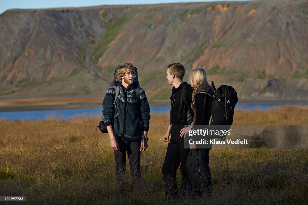 3 hikers talking together,mountain in background