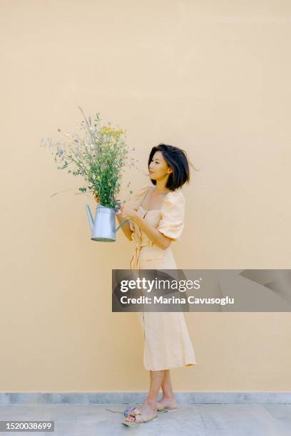 beautiful asian woman in summer dress enjoying natural beauty of  meadow flowers. - yellow dress stock-fotos und bilder