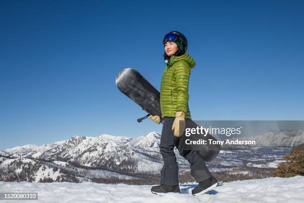 young woman snowboarder walking with her board in winter - women snowboarding stock pictures, royalty-free photos & images