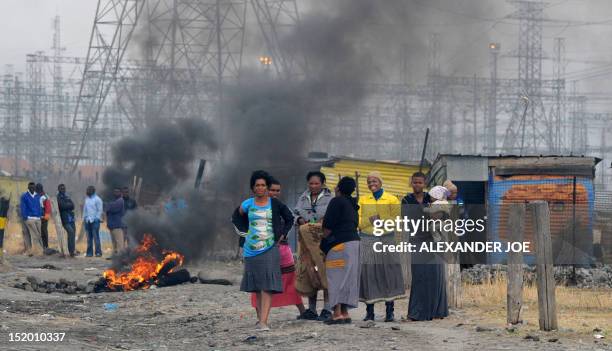 Striking miners stand after South African police fired tear gas in Marikana on September 15, 2012 at Lonmin's platinum mine after hundreds of workers...