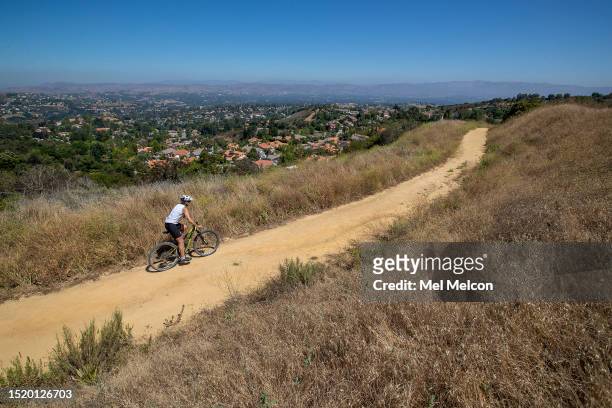 Bicycle rider makes his way past dry brush while pedaling along the Summit to Summit Trail in Calabasas.