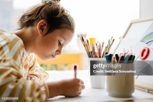 8 years girl painting with felt-tip pen. whiteboard of wood tabletop easel with her drawings - art therapy stock pictures, royalty-free photos & images