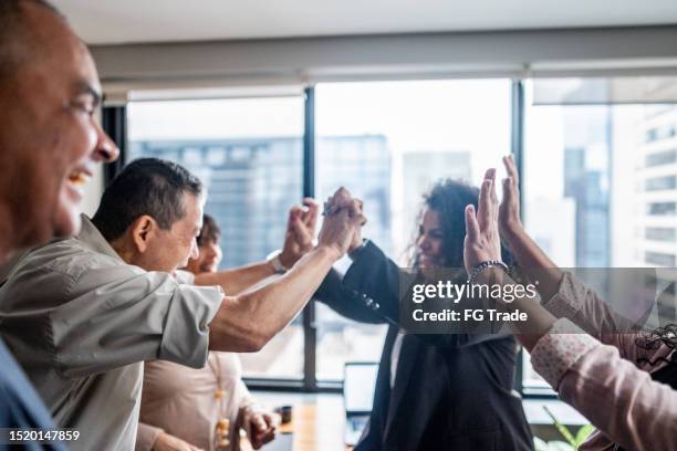 coworkers celebrating with intertwined hands at office - diverse professionals hands stockfoto's en -beelden