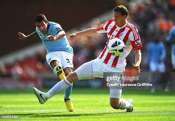 Carlos Tevez of Manchester City shoots at goal under pressure from Robert Huth of Stoke City during the Barclays Premier League match between Stoke...