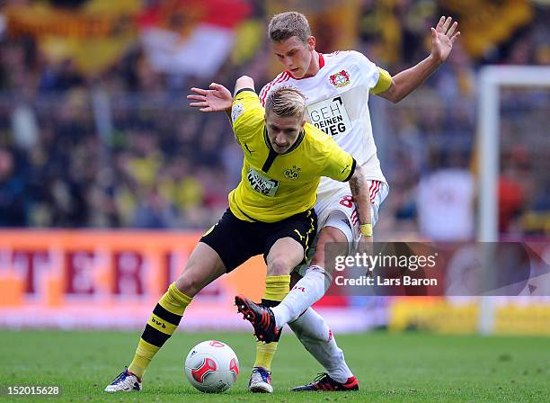 Marco Reus of Dortmund is challenged by Lars Bender of Leverkusen during the Bundesliga match between Borussia Dortmund and Bayer 04 Leverkusen at...