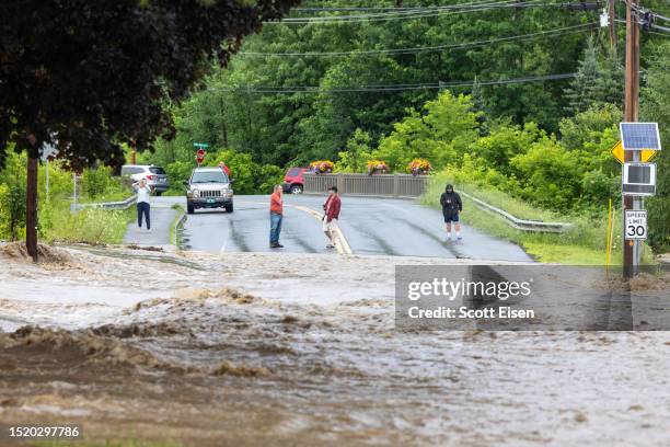 Onlookers check out a flooded road on July 10, 2023 in Chester, Vermont. Torrential rain and flooding has affected millions of people from Vermont...