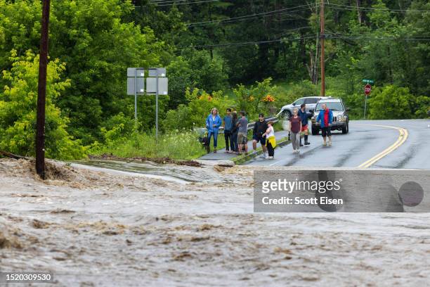 Onlookers check out a flooded road on July 10, 2023 in Chester, Vermont. Torrential rain and flooding has affected millions of people from Vermont...