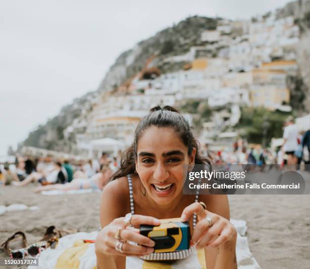 a woman uses a disposable camera on a beach - travel essentials stock pictures, royalty-free photos & images