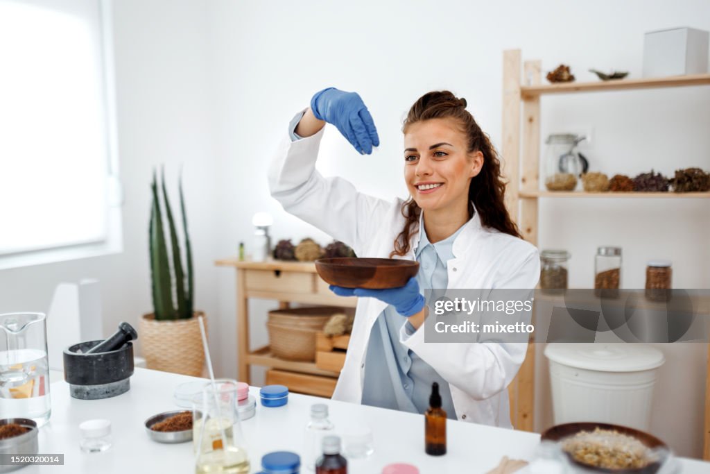 Young beautiful woman working with jojoba wax at her workshop