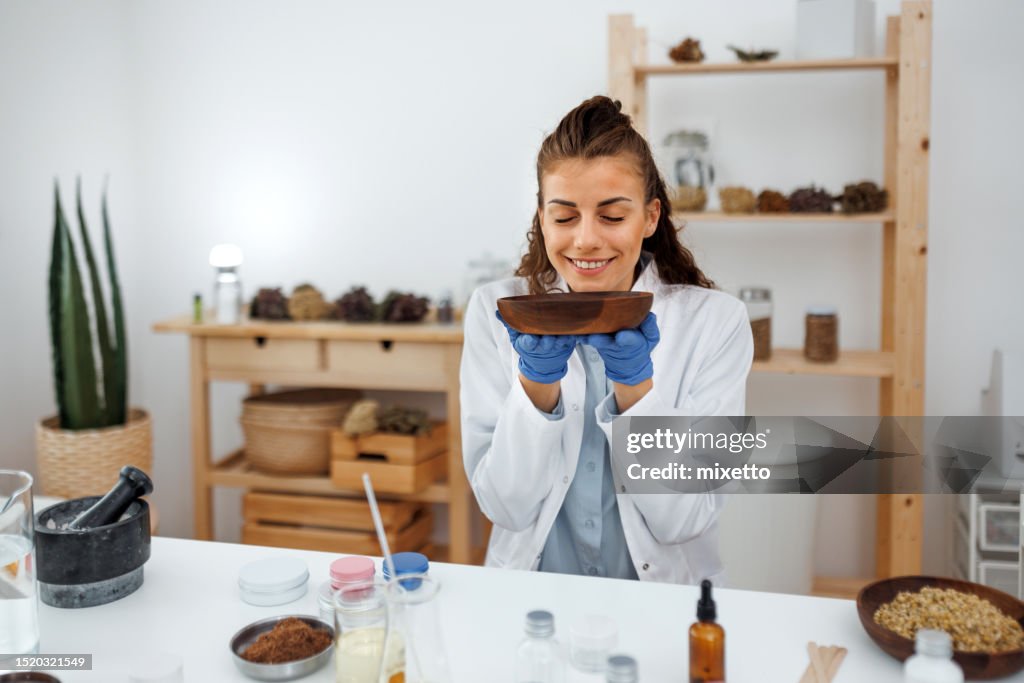 Young beautiful woman working with jojoba wax at her workshop