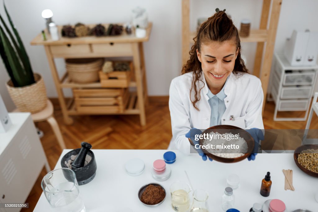 Young beautiful woman working with jojoba wax at her workshop