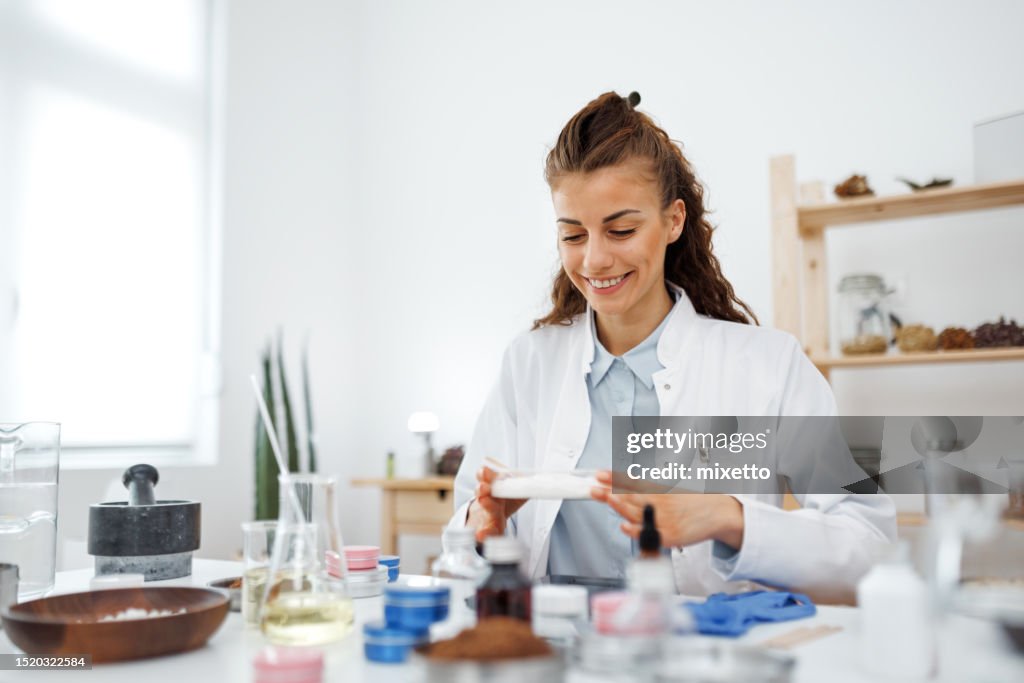 Young female scientist making homemade hands cream at her home based laboratory