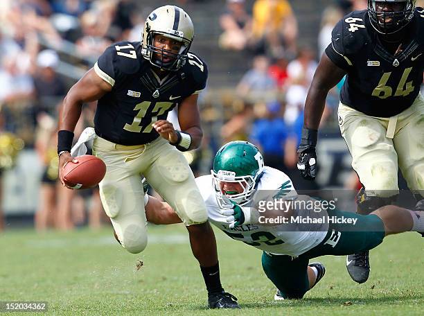 Quarterback Austin Parker of the Purdue Boilermakers runs away from the tackle of defensive lineman Pat O'Connor of the Eastern Michigan Eagles at...