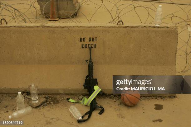 Plastic bottles of water, a M4 rifle and an extra basketball lie on a concrete barrier while US soldiers of 1st Battalion, 9th Field Artillery...