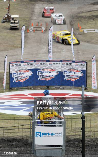 Officials watch racers head back to the pits after a hot lap session during the Port-A-Cool U.S. National Dirt Track Championship at Texas Motor...
