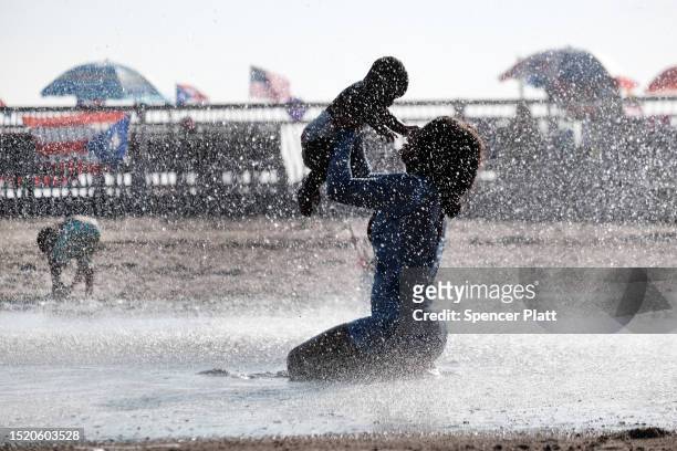 Mother and child cool off under a fountain in Coney Island on a hot afternoon on July 06, 2023 in the Brooklyn borough of New York City. As global...