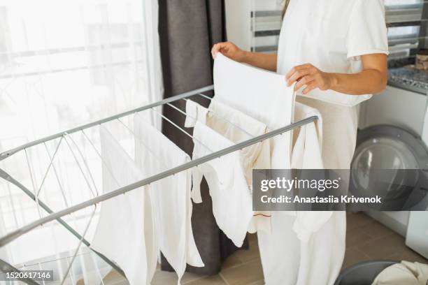 mother and little girl hanging clothes after laundry on the rack to dry. - vestito bianco foto e immagini stock
