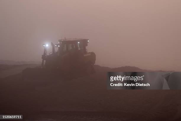 Contractors with the Army Corp of Engineers move sand as it is pumped from the ocean as part of a beach and dune replenishment project on July 06,...