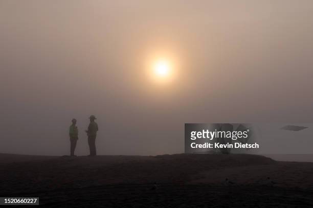 Contractors with the Army Corp of Engineers stand together at sunrise as they work on a beach and dune replenishment project on July 06, 2023 in...