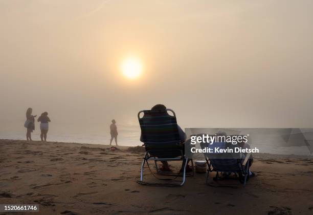 Beachgoers take in the morning sunrise as the Army Corp of Engineers continues their beach and dune replenishment project on July 06, 2023 in Bethany...
