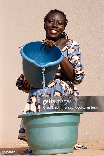 woman pours water in bucket - daily bucket stock-fotos und bilder