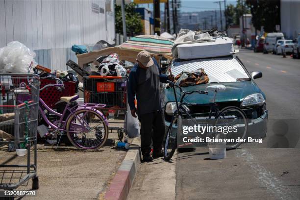 Canoga Park, CA A homeless man sweeps up around a sidewalk encampment on Deering Avenue on Monday, July 10, 2023 in Canoga Park, CA.