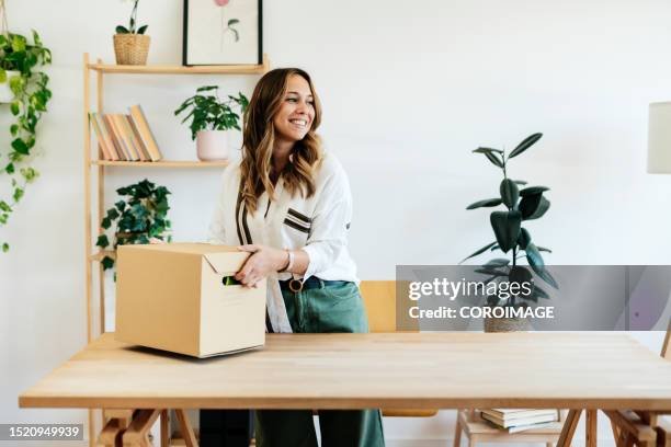 young businesswoman holding a box in the new office. concept of entrepreneurship and feminism. - opening day fotografías e imágenes de stock