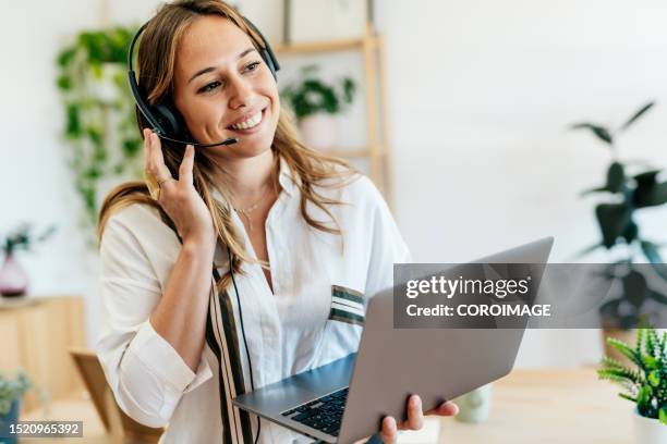 young adult woman in remote work meeting using a headset with microphone. - call centre stock pictures, royalty-free photos & images