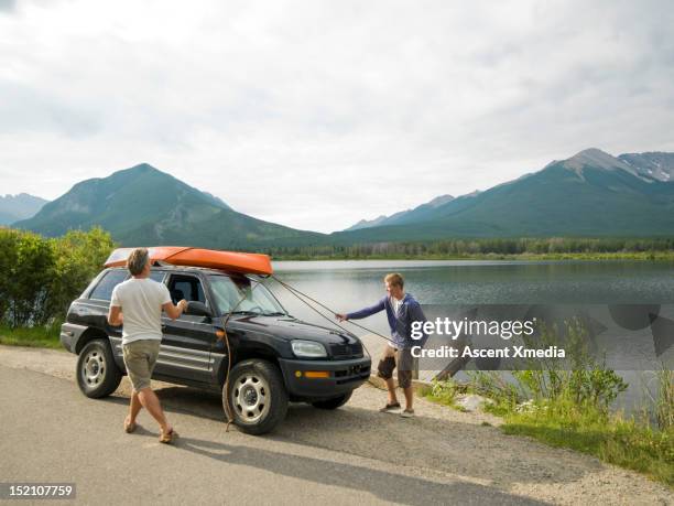 father and son removes kayak from car rooftop - on top of car stock pictures, royalty-free photos & images