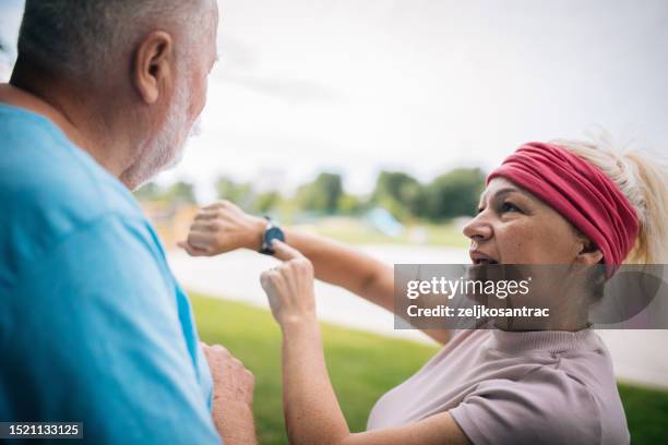 un couple d’âge mûr dans le sport fait du jogging ensemble et vérifie l’heure à la smartwatch - podomètre photos et images de collection