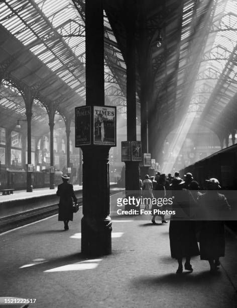 Posters advertise The Times newspaper fixed to pillars as rail passengers pass along a platform at Liverpool Street station in the City of London,...